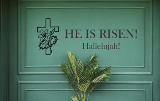 Large 'He is Risen' professional vinyl scripture decal displayed prominently on a church sanctuary wall for Easter worship.