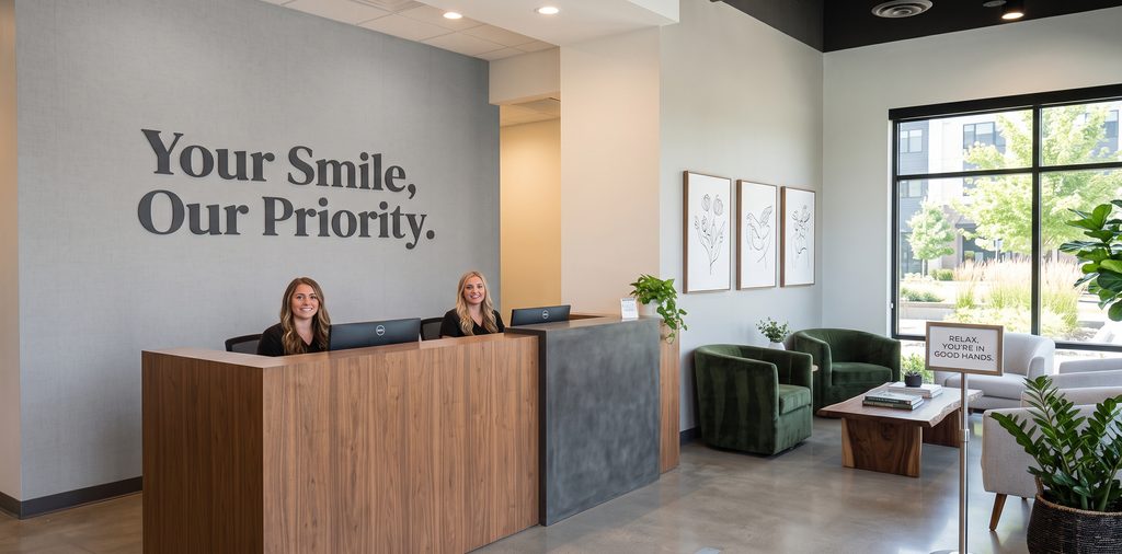 A modern dental office reception desk with professional vinyl wall lettering that reads 'Your Smile, Our Priority.' The background wall provides a clean focal point for patients entering the waiting area.